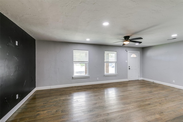 interior space with a ceiling fan, visible vents, baseboards, and wood finished floors