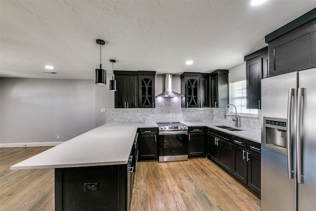 kitchen with stainless steel appliances, tasteful backsplash, light countertops, a sink, and wall chimney exhaust hood