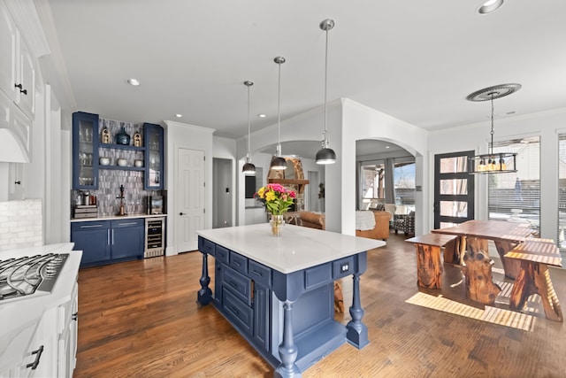 kitchen with arched walkways, blue cabinetry, wine cooler, and a healthy amount of sunlight