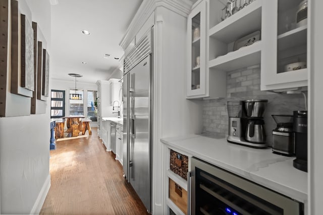 kitchen with tasteful backsplash, wine cooler, appliances with stainless steel finishes, wood finished floors, and white cabinetry