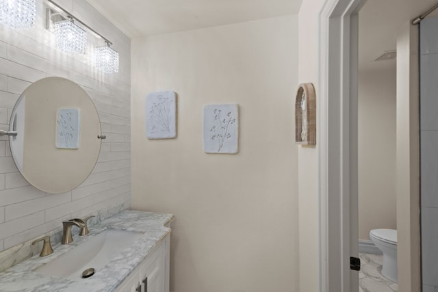 bathroom featuring toilet, marble finish floor, tasteful backsplash, and vanity