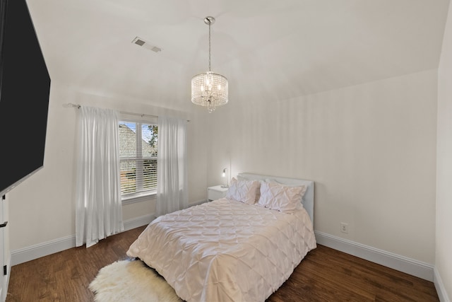 bedroom with visible vents, a notable chandelier, baseboards, and wood finished floors