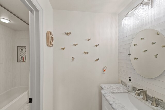 bathroom with shower / bathtub combination, backsplash, vanity, and tile walls