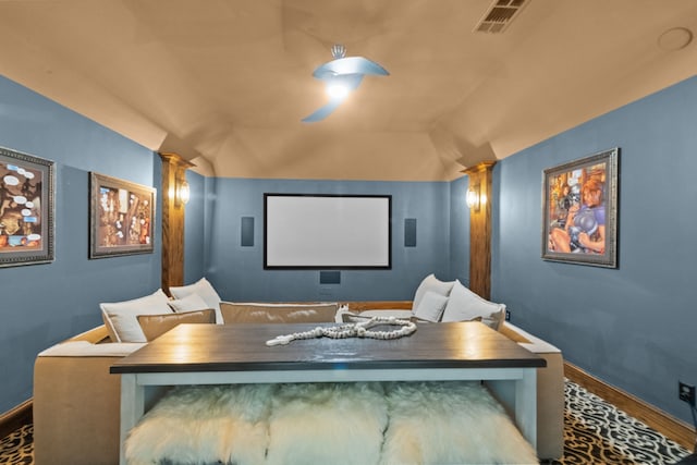 cinema room with decorative columns, lofted ceiling, visible vents, wood finished floors, and baseboards