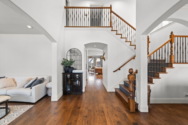 entrance foyer with arched walkways, wood finished floors, and baseboards