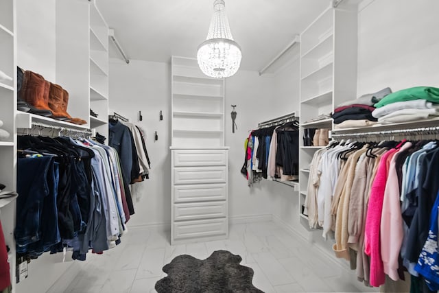 walk in closet featuring marble finish floor and a notable chandelier