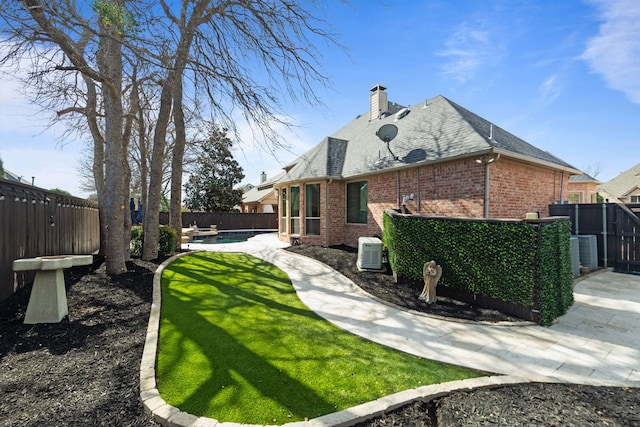 rear view of property with a fenced backyard, a chimney, a fenced in pool, and brick siding