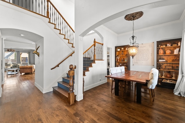 dining space with arched walkways, dark wood-style flooring, baseboards, ornamental molding, and stairway