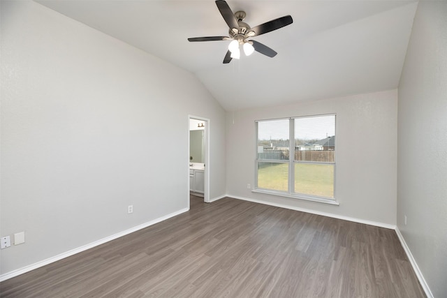 spare room with lofted ceiling, baseboards, and wood finished floors