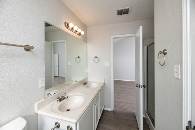 full bath with a shower stall, visible vents, a sink, and wood finished floors