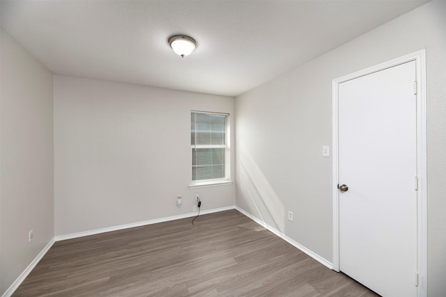 unfurnished room with baseboards and wood finished floors