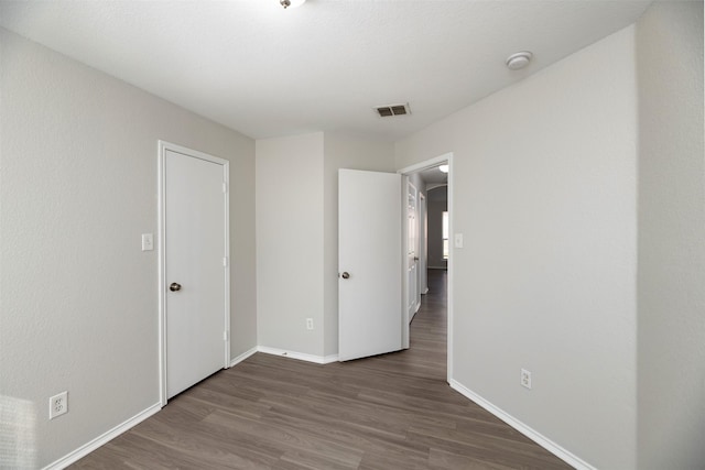 unfurnished bedroom featuring dark wood-style floors, baseboards, and visible vents