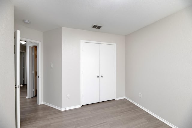 unfurnished bedroom featuring wood finished floors, visible vents, and baseboards