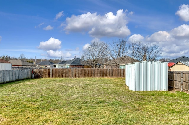 view of yard with a storage shed, a fenced backyard, and an outbuilding