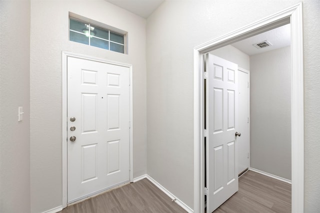 foyer entrance featuring visible vents, baseboards, and wood finished floors