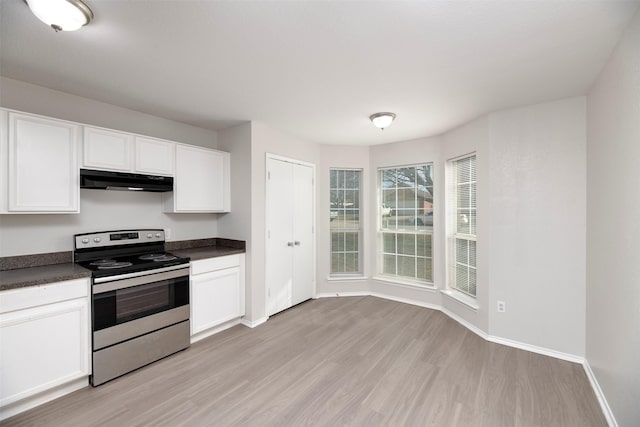 kitchen with light wood-style flooring, under cabinet range hood, electric range, white cabinets, and dark countertops