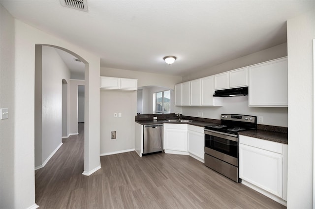 kitchen with under cabinet range hood, a sink, visible vents, appliances with stainless steel finishes, and dark countertops