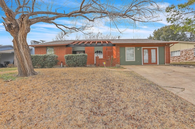 ranch-style house featuring a front yard, french doors, and brick siding