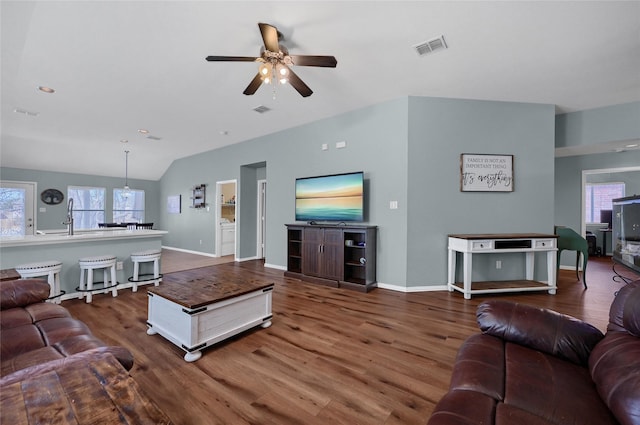 living area with lofted ceiling, baseboards, visible vents, and wood finished floors