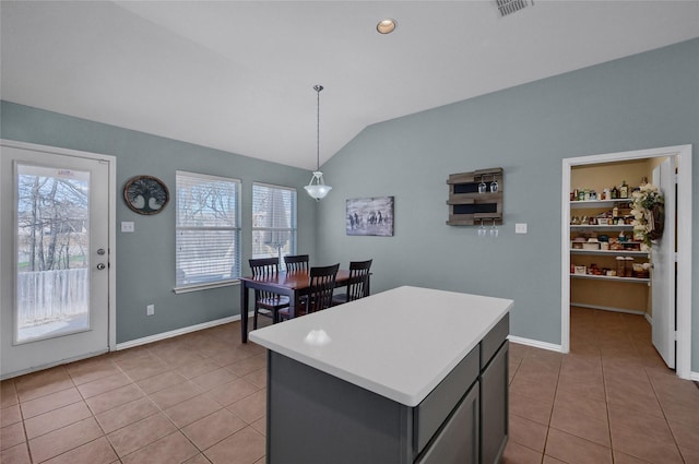 kitchen featuring a kitchen island, vaulted ceiling, light countertops, and light tile patterned flooring