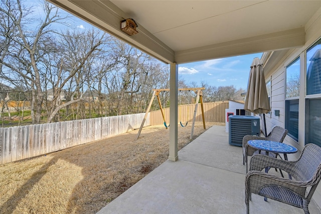 view of patio / terrace with central AC unit, a playground, and a fenced backyard