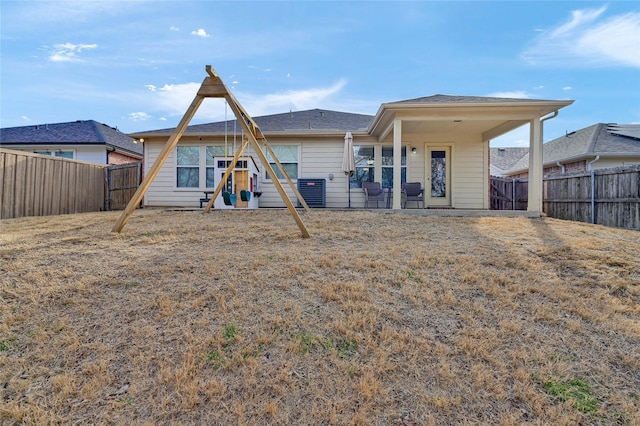 rear view of property featuring cooling unit, a fenced backyard, and a playground