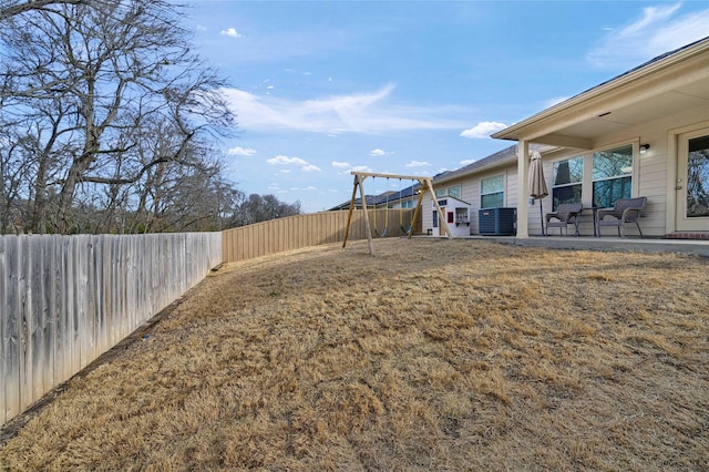 view of yard featuring a playground, a fenced backyard, and central air condition unit