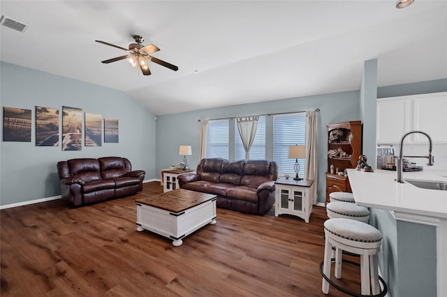 living area with ceiling fan, visible vents, baseboards, vaulted ceiling, and dark wood-style floors