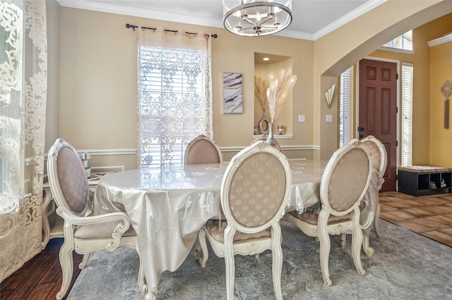 dining room with tile patterned flooring, arched walkways, a chandelier, and crown molding