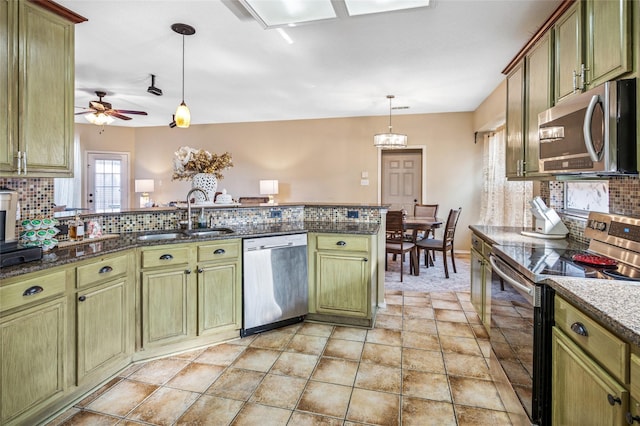 kitchen featuring stainless steel appliances, green cabinetry, a sink, decorative backsplash, and pendant lighting