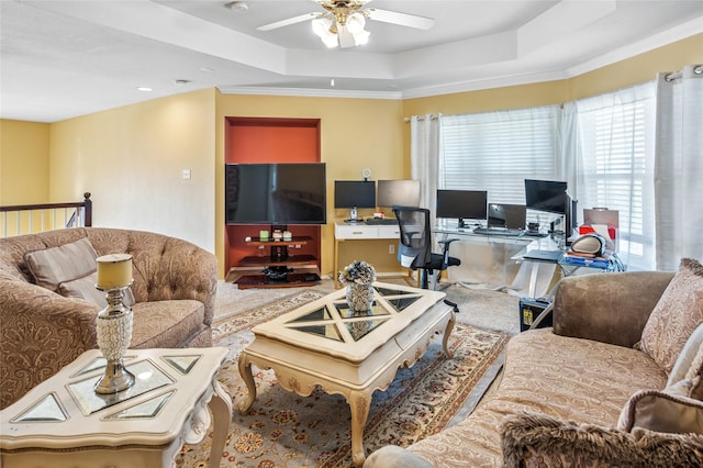 living room with a tray ceiling, a ceiling fan, and ornamental molding