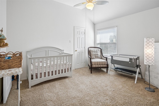 bedroom featuring carpet floors, a nursery area, vaulted ceiling, and a ceiling fan