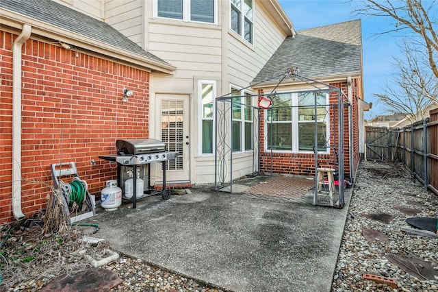 exterior space with a patio area, a shingled roof, a fenced backyard, and brick siding