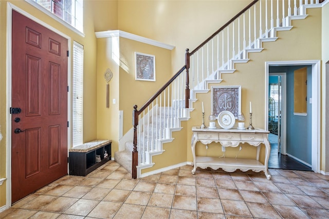 entryway featuring light tile patterned floors, stairway, a towering ceiling, and baseboards