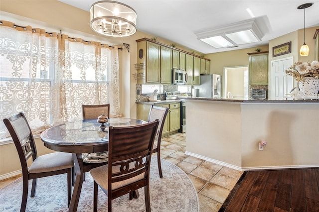 dining room featuring a chandelier, a toaster, baseboards, and light tile patterned floors