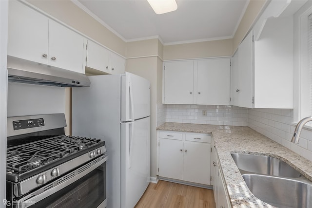 kitchen with under cabinet range hood, a sink, white cabinetry, ornamental molding, and gas range