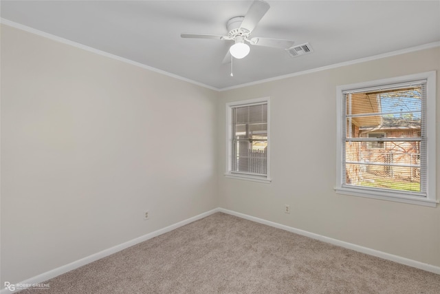 carpeted spare room featuring ornamental molding, a ceiling fan, visible vents, and baseboards