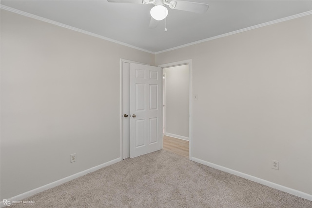 empty room with carpet floors, ornamental molding, baseboards, and a ceiling fan