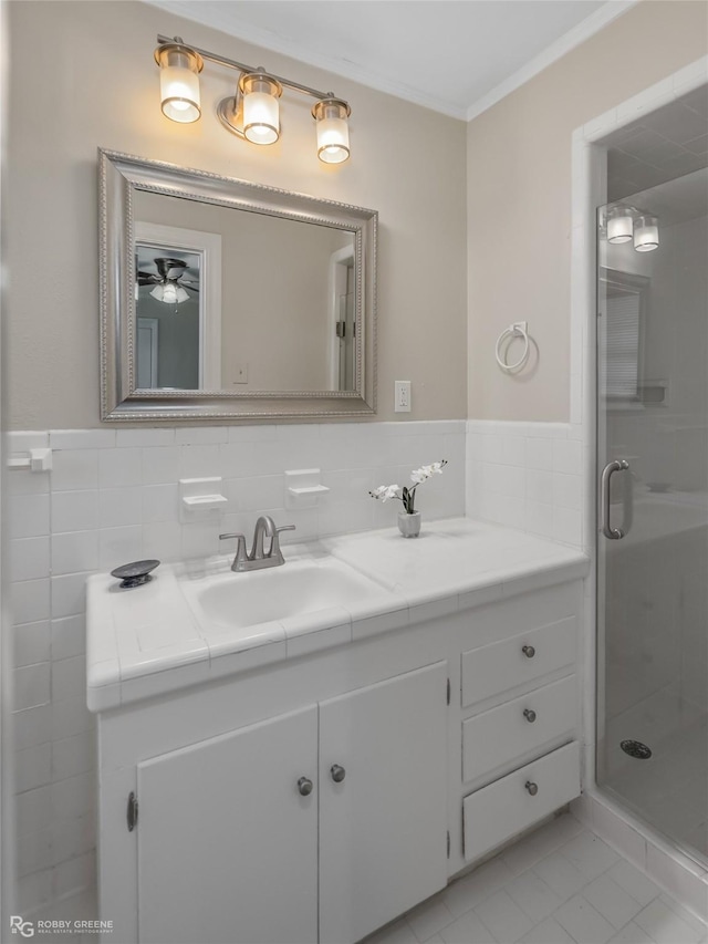 bathroom featuring tile walls, a shower stall, vanity, and crown molding