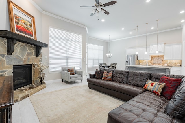 living room with recessed lighting, ceiling fan with notable chandelier, a fireplace, baseboards, and ornamental molding