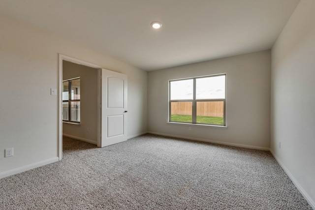 unfurnished room with carpet and baseboards