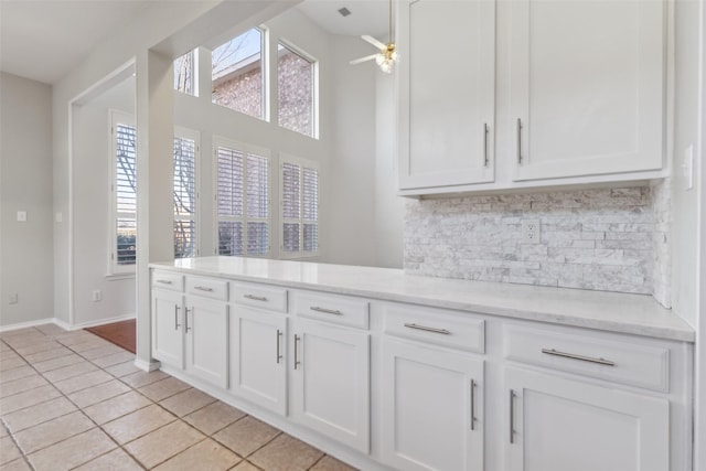 kitchen with light tile patterned floors, ceiling fan, baseboards, white cabinets, and tasteful backsplash