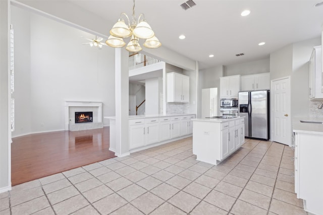 kitchen with visible vents, decorative backsplash, a kitchen island, stainless steel appliances, and light countertops