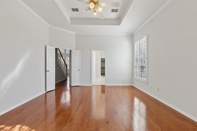 interior space with a raised ceiling, visible vents, baseboards, and wood finished floors