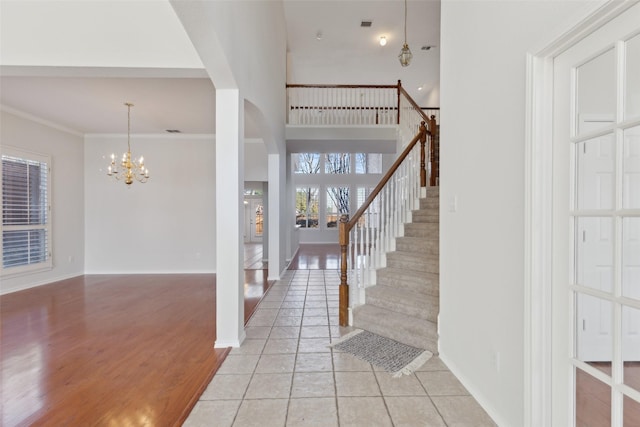 entrance foyer featuring baseboards, stairway, a notable chandelier, and crown molding