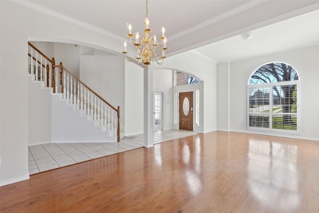 entrance foyer with crown molding, stairs, a chandelier, and wood finished floors