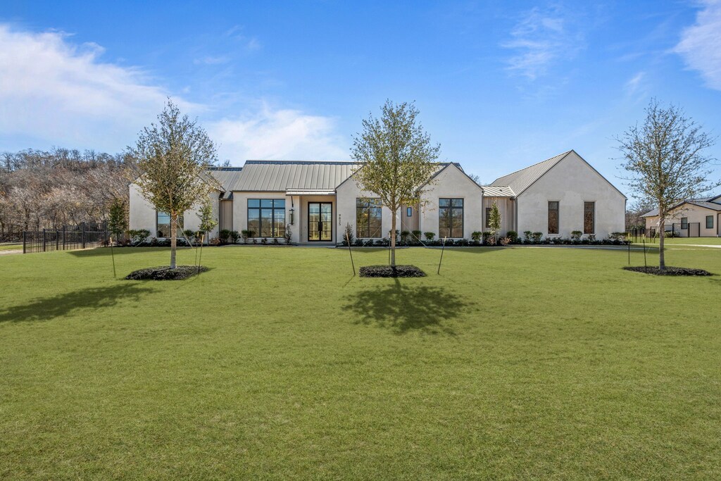 view of front of home with metal roof, french doors, stucco siding, a front lawn, and a standing seam roof