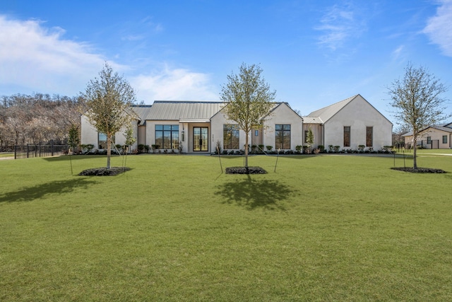 view of front of home with metal roof, french doors, stucco siding, a front lawn, and a standing seam roof