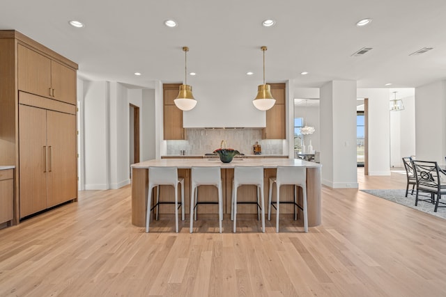 kitchen with light wood-type flooring, light countertops, and backsplash