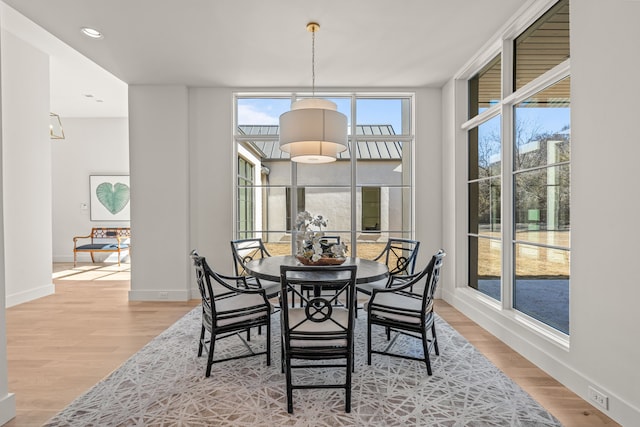 dining room with expansive windows, light wood-style flooring, and baseboards